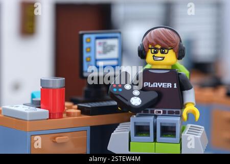 Tambov, Federazione Russa - 16 febbraio 2025 Una minifigura di un ragazzo di videogiochi Lego con un gamepad seduto su una sedia da gioco dietro un PC da gioco. Foto Stock