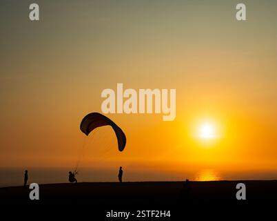 Un parapendio cerca di decollare sullo sfondo di un tramonto sull'Oceano Pacifico a Lima. Miraflores, Perù, Sud America Foto Stock