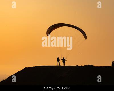 Un parapendio cerca di decollare sullo sfondo di un tramonto sull'Oceano Pacifico a Lima. Miraflores, Perù, Sud America Foto Stock