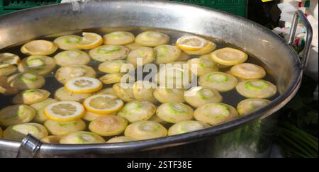Molti pezzi di carciofo tagliati immersi in una vasca di acqua di limone al mercato Foto Stock