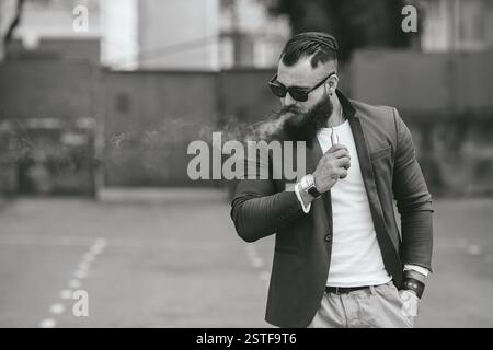 L'uomo con la barba fuma sigaretta elettronica Foto Stock