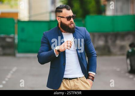 L'uomo con la barba fuma sigaretta elettronica Foto Stock