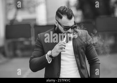 L'uomo con la barba fuma sigaretta elettronica Foto Stock