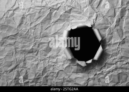Foglio di carta grigia deformata con un foro Foto Stock