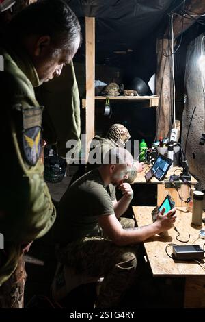 Ucraina. 22 dicembre 2024. All'interno di un bunker sotterraneo, gli operatori di droni ucraini volano un drone per colpire le posizioni russe in prima linea. La guerra tra Ucraina e Russia ha dimostrato quanto i droni economici e sacrificabili, come il kamikaze o i modelli che lanciano bombe, stiano rimodellando la guerra. Questi droni consentono attacchi precisi e a basso costo e si sono dimostrati estremamente efficaci nell'interrompere le operazioni nemiche. Di conseguenza, stanno cambiando le strategie militari, segnalando un futuro in cui i droni svolgono un ruolo centrale nel combattimento, riducendo la dipendenza dalle armi tradizionali e costose. (Immagine di credito: © Miguel Cande Foto Stock