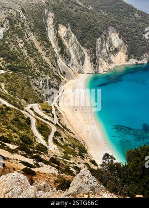 Una splendida vista aerea di una spiaggia isolata con acque turchesi, sabbia dorata e scogliere spettacolari. Una strada tortuosa conduce a questa costa mozzafiato Foto Stock