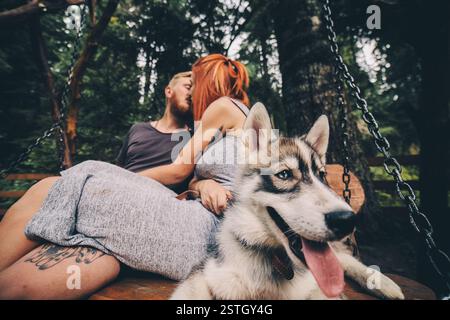 Bella coppia insieme al cane su un'altalena Foto Stock