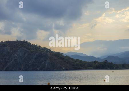 Lago tranquillo con montagne e cielo nuvoloso alla luce del mattino presto Foto Stock