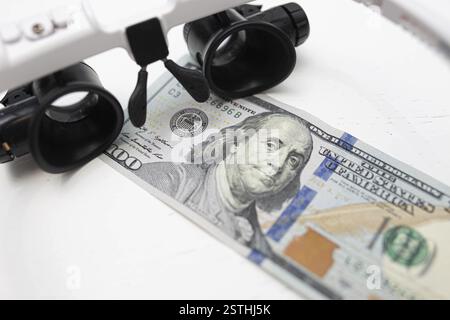 Lenti d'ingrandimento per un conto di oltre cento dollari, evidenziando l'ispezione finanziaria Foto Stock
