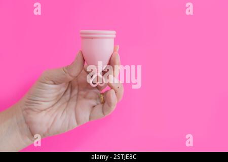 Coppetta mestruale rosa riutilizzabile, igiene femminile isolata su sfondo rosa. Concetto zero rifiuti. Foto Stock