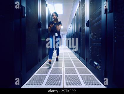 Tecnico femminile che cammina nella sala server Foto Stock