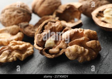 Noci mature fresche e conchiglie sul tavolo nero, primo piano Foto Stock