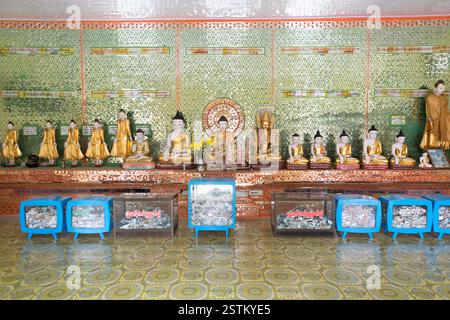 Myanmar, Mandalay, fila di statue di Buddha e scatole per donazioni. Foto Stock