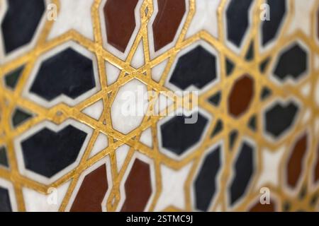 I motivi geometrici dorati sulle piastrelle di marmo mostrano un'intricata arte del design islamico, combinando simmetria ed eleganza in una splendida disposizione a mosaico Foto Stock