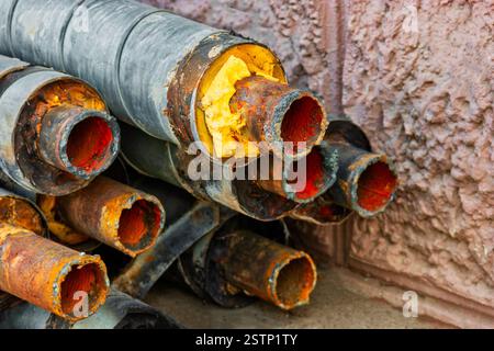 Riparazione di condutture idriche. Tubo in acciaio arrugginito con isolamento nel cantiere in un involucro per tubi in plastica che si trova sul cortile Foto Stock