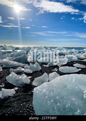 La foto cattura un paesaggio mozzafiato caratterizzato da una spiaggia disseminata di grandi frammenti di ghiaccio Foto Stock