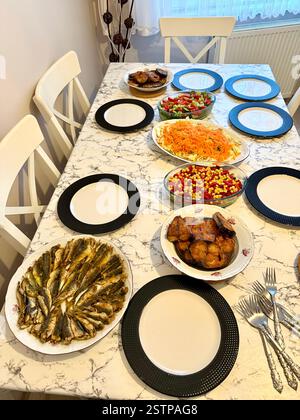 La grande famiglia ha una cena con pesce fresco palamut di bonito e acciughe insalata istavrit pasto cucinato sul tavolo pronto da mangiare Foto Stock