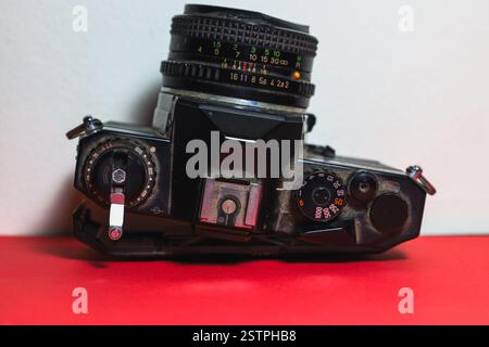 Vista dall'alto ravvicinata di una vecchia fotocamera reflex nera con polvere visibile, graffi e segni di usura Foto Stock