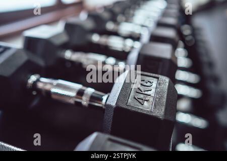 Avvicinati a molti manubri in metallo sul rack nel centro fitness sportivo. Foto Stock