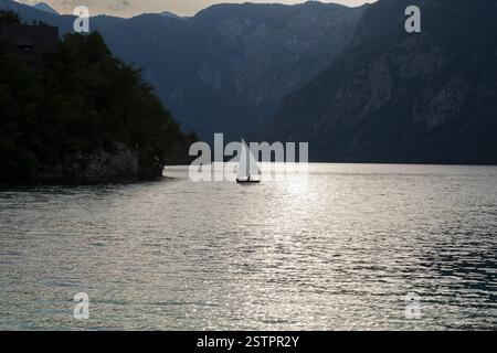 Vista panoramica di una barca a vela su un lago nebbioso, Bohinj. Slovenia Foto Stock