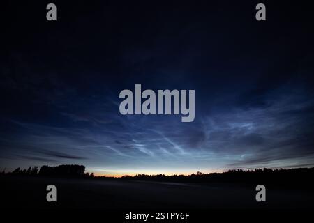 Una vista mozzafiato di nuvole nocciolenti che si illuminano nelle sfumature blu profonde di un cielo notturno estivo. Foto Stock
