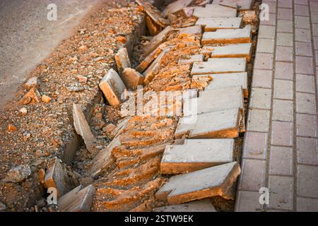 Costruzione di mucchi di sabbia, pietre adagiate sul marciapiede vicino ai pozzi per l'installazione tra la carreggiata e il sentiero. Brok Foto Stock