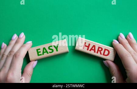 Simbolo facile o duro. Parola concettuale Easy or hard su blocchi di legno. Mano d'affari. Bellissimo sfondo verde. Business e concetto facile o difficile. Copia Foto Stock