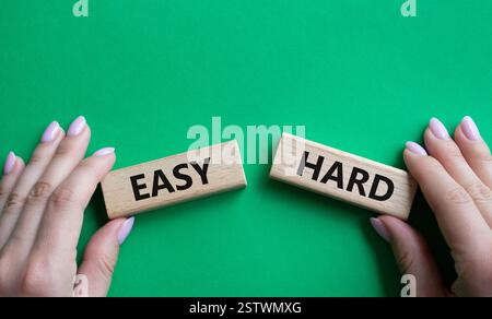 Simbolo facile o duro. Parola concettuale Easy or hard su blocchi di legno. Mano d'affari. Bellissimo sfondo verde. Business e concetto facile o difficile. Copia Foto Stock
