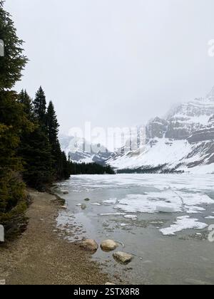 La foto cattura un tranquillo paesaggio caratterizzato da un lago circondato da montagne maestose. La scena è dominata da un cielo nuvoloso Foto Stock