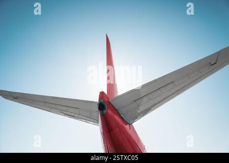Vista ad angolo basso. di una coda di un aereo rosso. Ripresa retroilluminata dell'assemblaggio della coda dell'aereo - impennaggio dell'aereo commerciale. Foto Stock