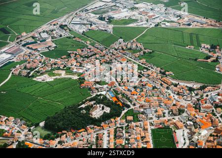 Vista dall'alto di una piccola città nel nord Italia. Piccola città ai piedi delle montagne. Foto Stock