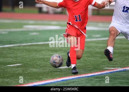 Due giocatori si scontrano mentre cercano di ottenere il possesso della palla da calcio sul campo da prato. Foto Stock
