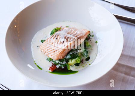 Filetto di salmone scottato in padella servito su un letto di verdure saltate in una salsa cremosa Foto Stock