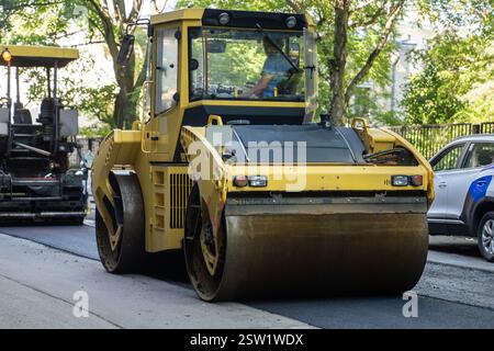 Rullo per la posa di asfalto caldo fresco sulla strada. Attrezzature per la costruzione di strade. Foto Stock