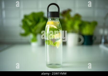 Acqua con menta, timo, calce per bere all'aperto quando fa caldo, bottiglia con acqua di menta e limone Foto Stock