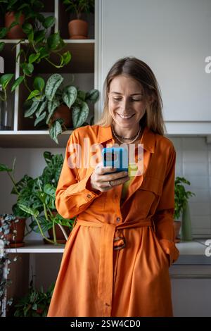 Una donna scandinava felice e sicura di sé che chatta sullo smartphone scrivendo un messaggio sorridente guardando lo schermo. Foto Stock