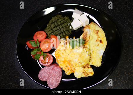 omelette salsiccia pomodori, pesto di pasta e feta su piatto, colazione, pranzo, piatti neri. Riprese 4K di alta qualità Foto Stock