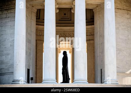 WASHINGTON DC - la sagoma della statua di Thomas Jefferson è visibile attraverso le colonne del Jefferson Memorial alla luce del mattino. La statua di bronzo di 19 piedi, creata dallo scultore Rudulph Evans, rimane in ombra all'interno della rotonda, mentre la luce del sole illumina le colonne di marmo esterne del monumento. Il profilo laterale crea un drammatico contrasto tra luce e ombra in questa vista del monumento neoclassico. Foto Stock
