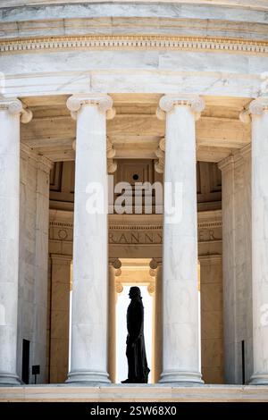 WASHINGTON DC - la sagoma della statua di Thomas Jefferson è visibile attraverso le colonne del Jefferson Memorial alla luce del mattino. La statua di bronzo di 19 piedi, creata dallo scultore Rudulph Evans, rimane in ombra all'interno della rotonda, mentre la luce del sole illumina le colonne di marmo esterne del monumento. Il profilo laterale crea un drammatico contrasto tra luce e ombra in questa vista del monumento neoclassico. Foto Stock