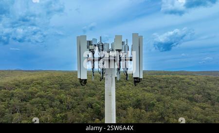 Fotografia aerea con drone della sezione superiore di una torre di telecomunicazioni dotata di antenne e apparecchiature di trasmissione utilizzate per le comunicazioni. Foto Stock