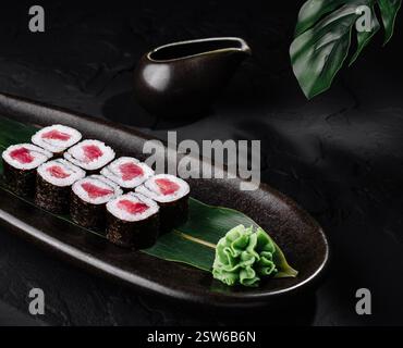 Elegante presentazione di sushi roll di tonno su sfondo scuro Foto Stock