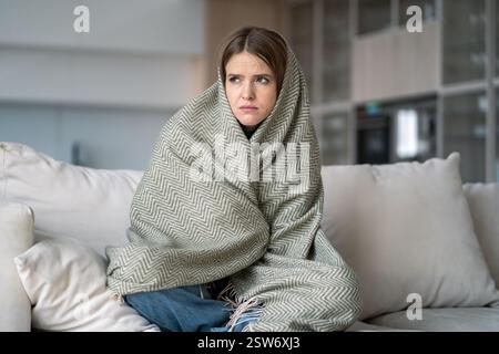 Donna solitaria avvolta in coperta sedersi sul divano, sentire depressione, tristezza, esaurimento emotivo, malattia Foto Stock