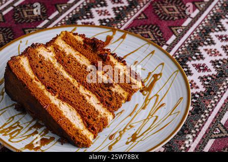 Deliziosa fetta di torta con impasti di miele su una tovaglia a motivi geometrici Foto Stock