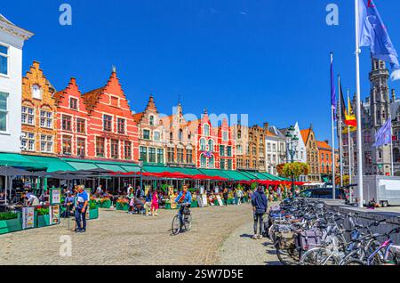 Bruges, Belgio, 5 luglio 2023: Edifici in stile barocco fiammingo con facciate colorate, ristoranti di strada e caffetterie terrazzate sulla piazza del mercato i Foto Stock