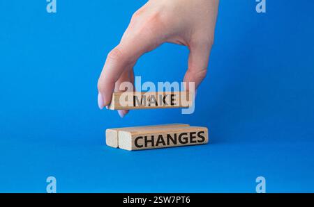 Apportare modifiche. I blocchi di legno con le parole apportano modifiche. Bellissimo sfondo blu. Mano d'affari. Concetto di business e di make change. Copia spazio Foto Stock