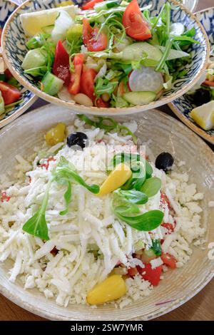 Insalate fresche con verdure varie e un abbondante condimento di formaggio sbriciolato Foto Stock