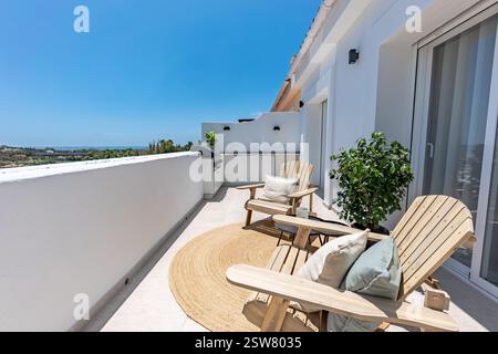 un'immagine di un balcone privato con sedie in legno e cucina all'aperto in un lussuoso appartamento mediterraneo Foto Stock
