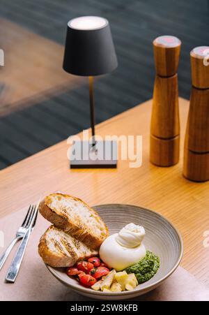 Deliziosa insalata di burrata servita sul tavolo del ristorante con fette di pane tostato Foto Stock