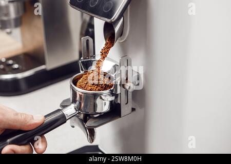 Riempimento del portafiltro con caffè appena macinato per la preparazione dell'espresso Foto Stock