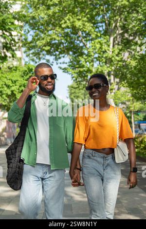 Una coppia afroamericana che ama camminare tenersi per mano in città e fare ridere la fidanzata. Foto Stock